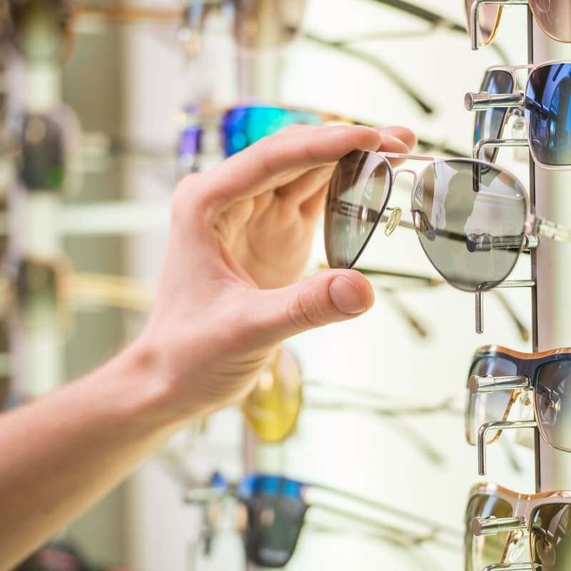 benefits of sunglasses, person taking a pair of glasses off a shelf | e-Surgery