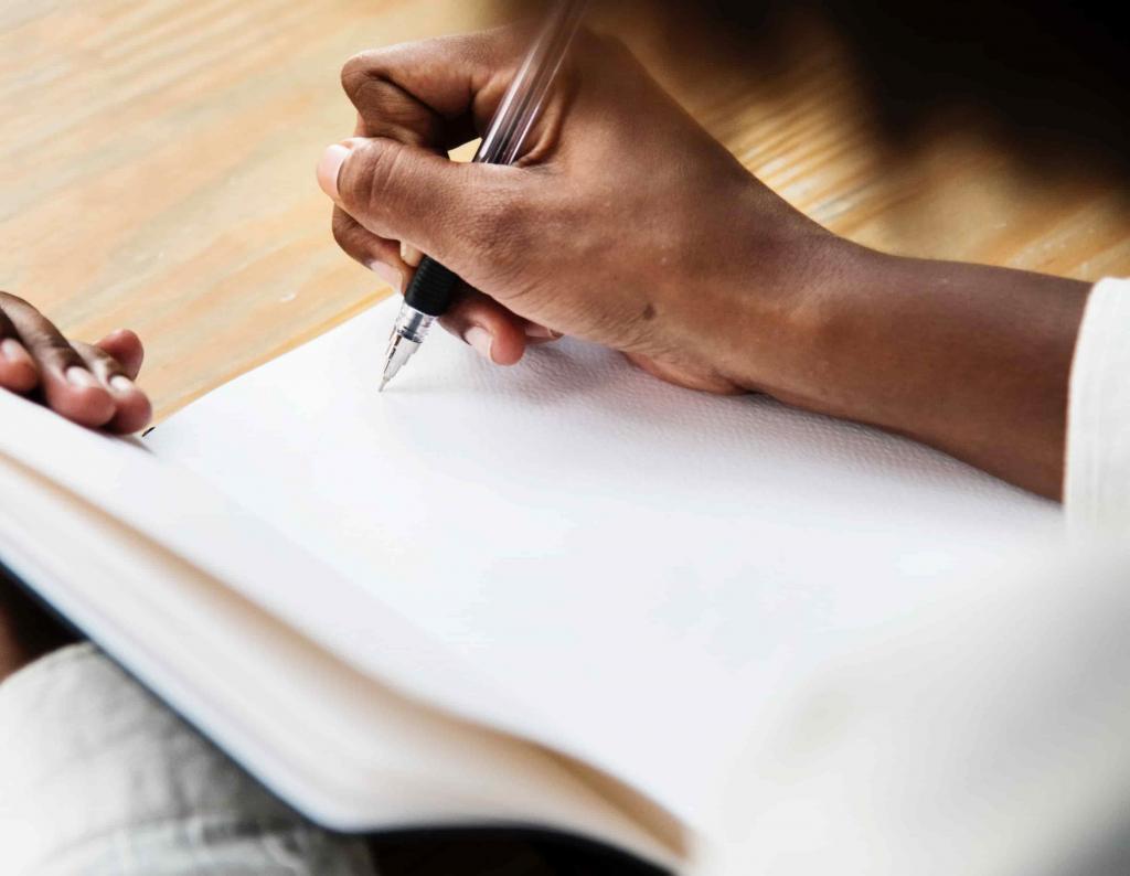 Person writing in a blank notebook, tracking migraine symptoms, e-Surgery