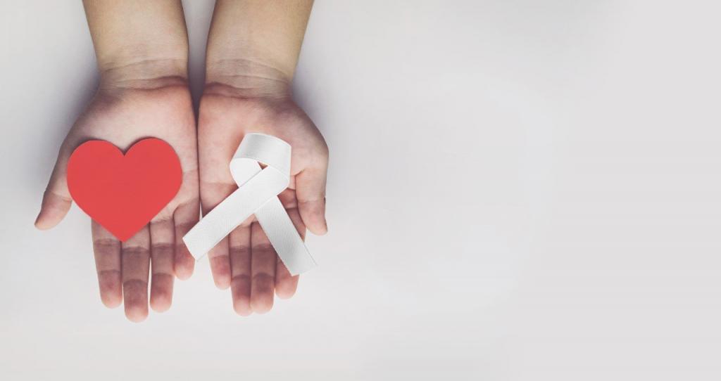 A pair of hands holding a paper heart and a white ribbon | The Dark Side of Christmas: The Rise of Domestic and Sexual Abuse During the Festive Period | e-Surgery