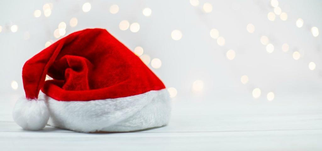 Red Santa hat on a white table, fairy lights are glowing in the background | The Dark Side of Christmas: The Rise of Domestic and Sexual Abuse During the Festive Period | e-Surgery
