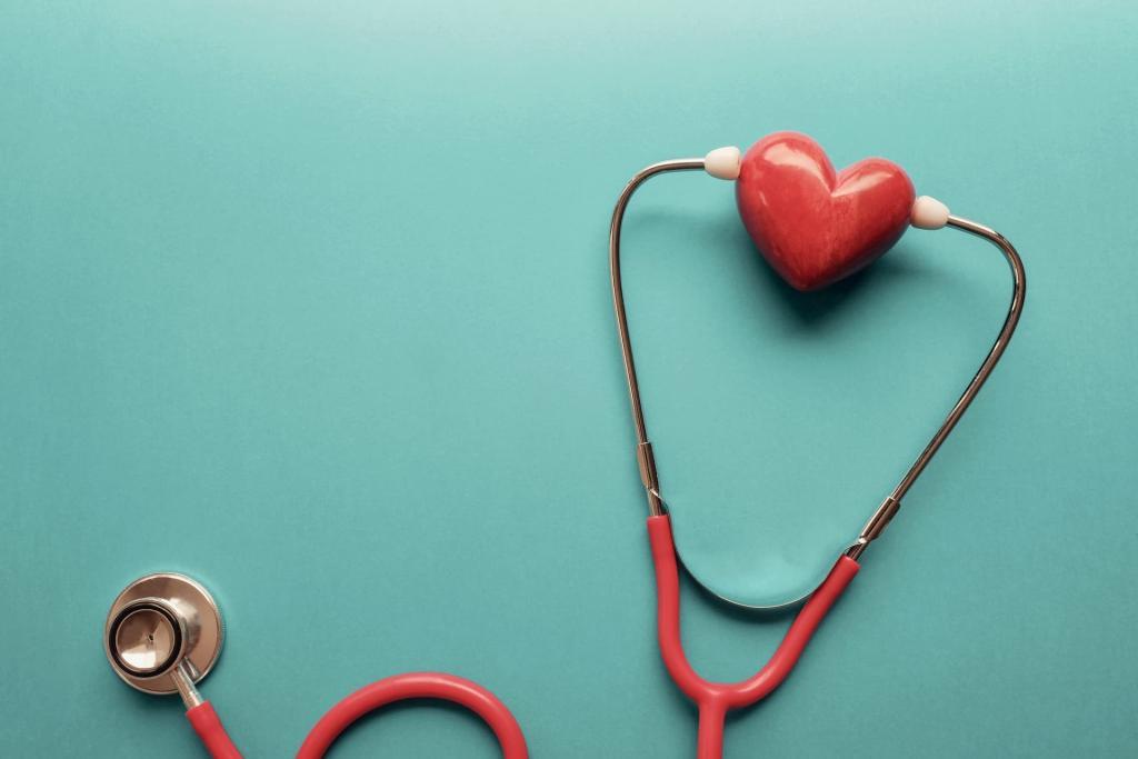 Red stethoscope with a marble red heart between the ear pieces resting on a green surface. This image indicates a healthy heat that could be achieved with use of statins to treat high cholesterol | Statin Side Effects: Should You Be Scared? | e-Surgery