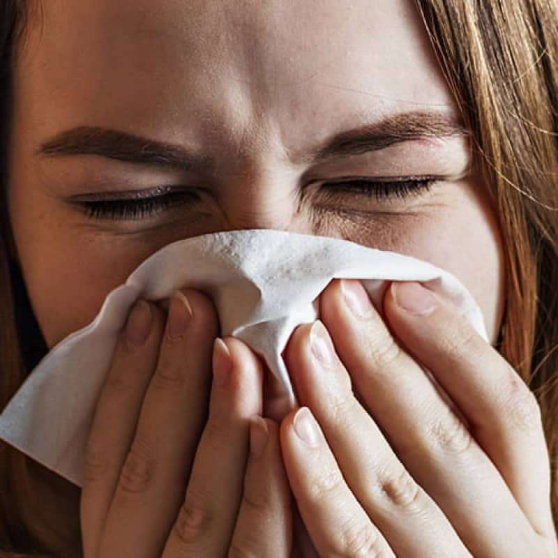 Woman blowing nose using tissue, pollen guide to seasonal asthma, e-Surgery