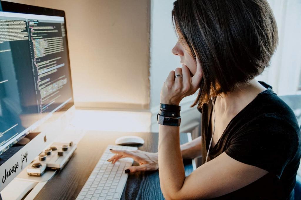 Young female with short hair sitting at a desk resting her chin on her hand and typing on a keyboard with her other. Her computer screen is filled with code | Period-tech: 5 Ways Technology is Changing Women’s Health | e-Surgery