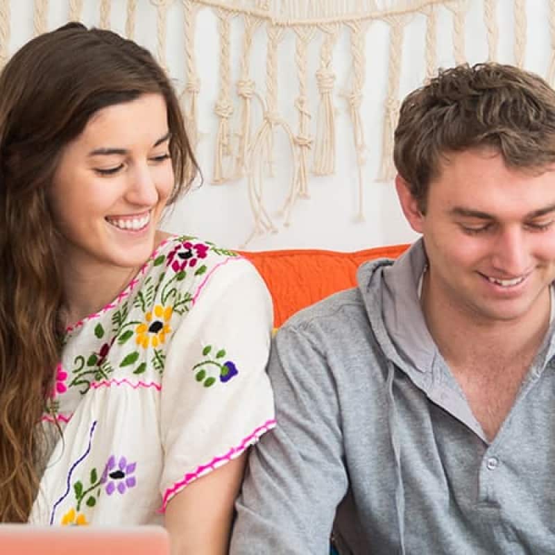 Young couple sitting on a sofa looking at at an electronic tablet in the males hands | e-Surgery