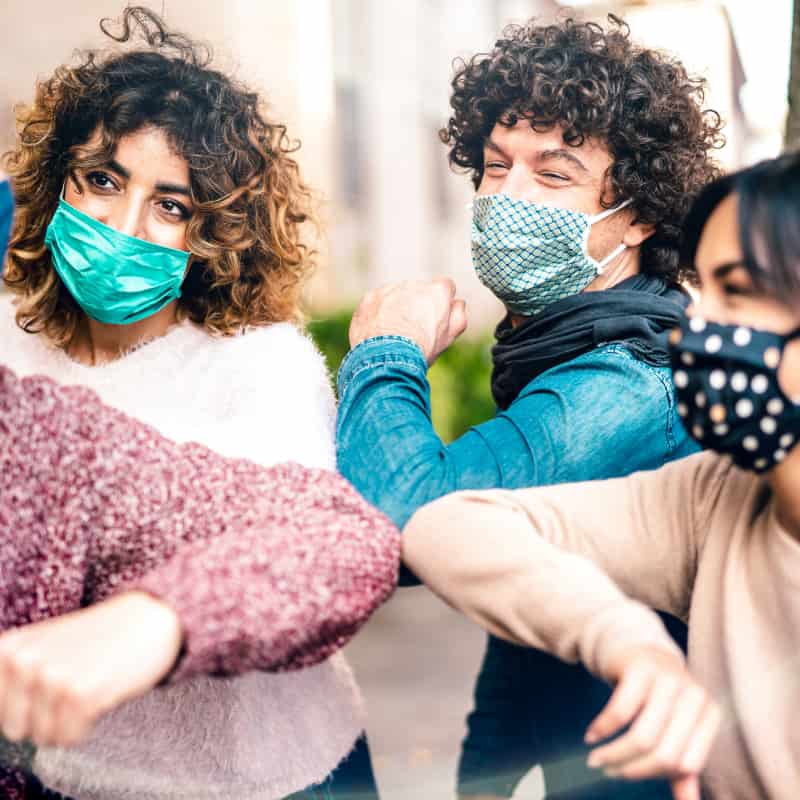 People bumping elbows wearing masks | e-Surgery