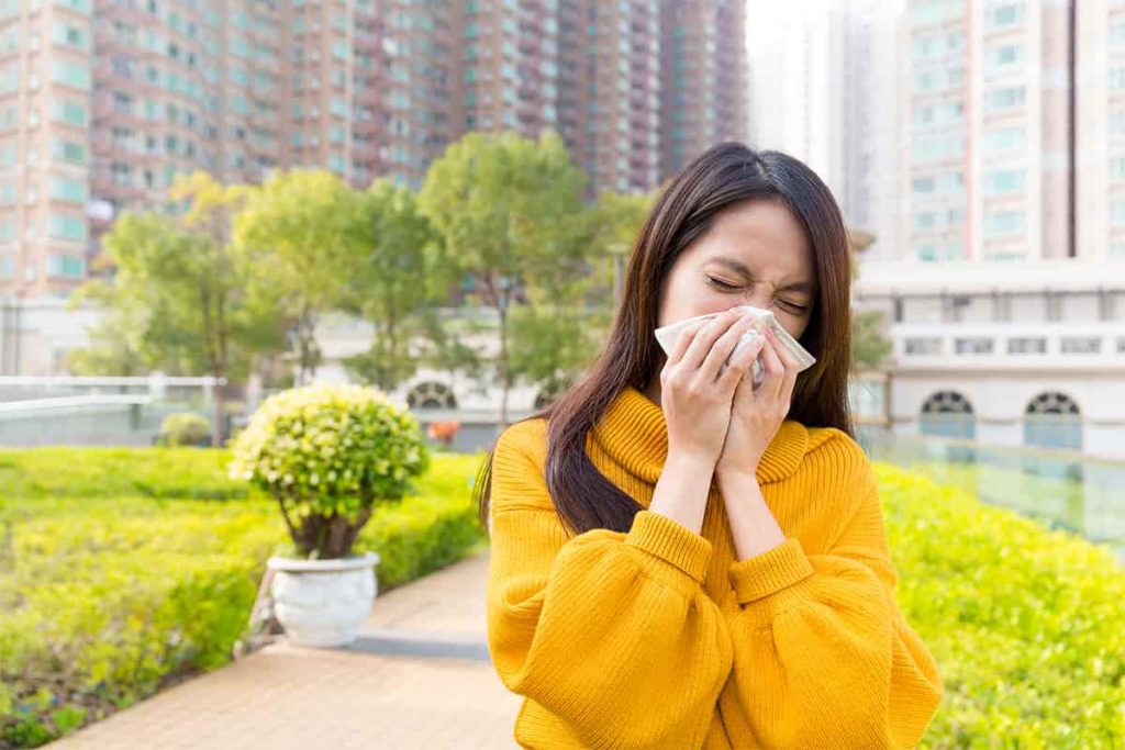 Woman sneezing in yellow jumper