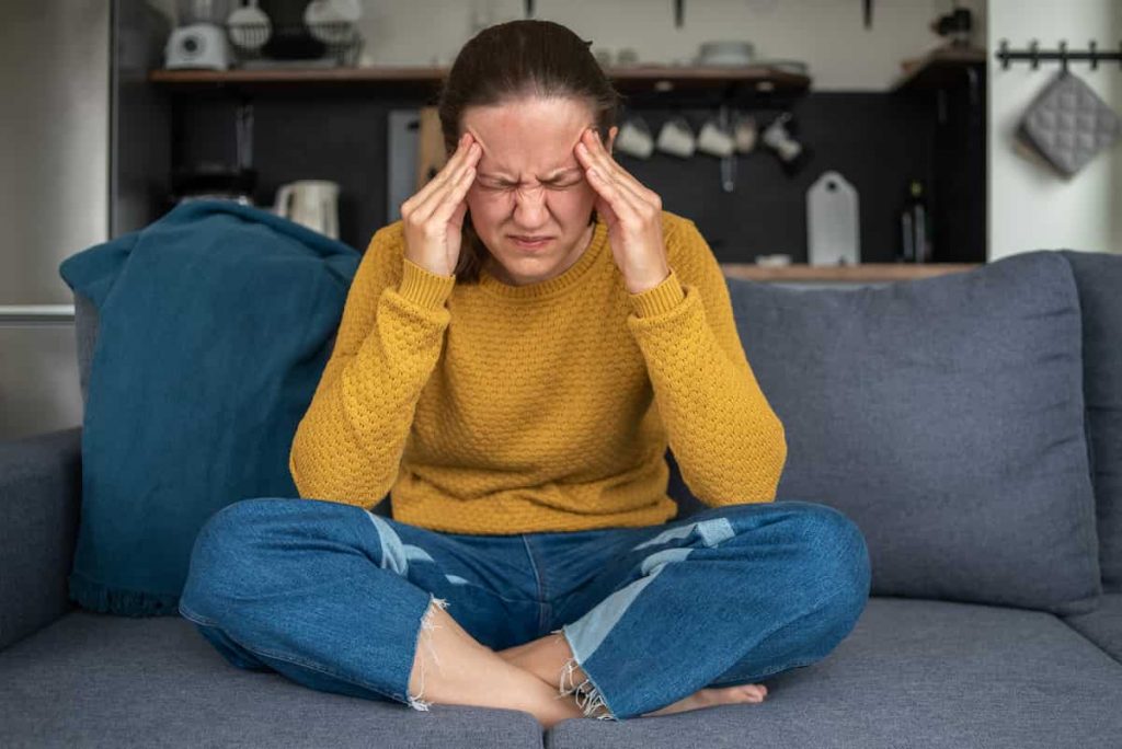 How common is herpes in the UK? | Woman holding her head in her hands with a headache | e-Surgery