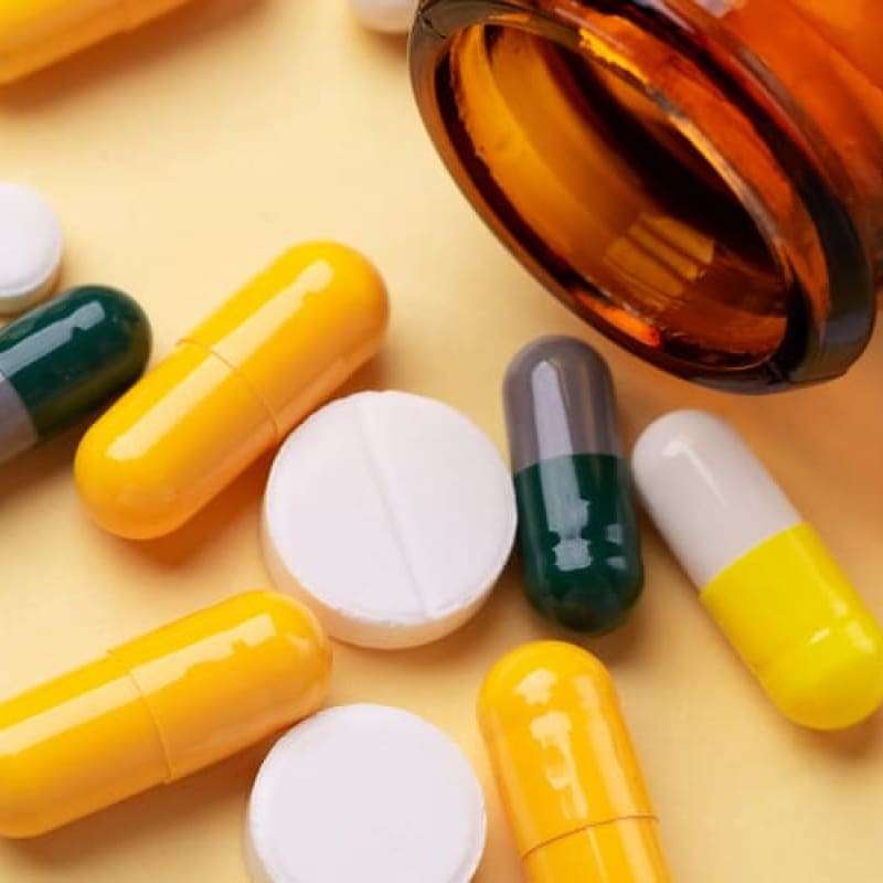 Bottle with pills falling out on yellow background