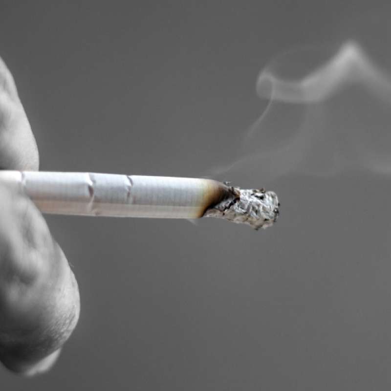 Man holding burning cigarette
