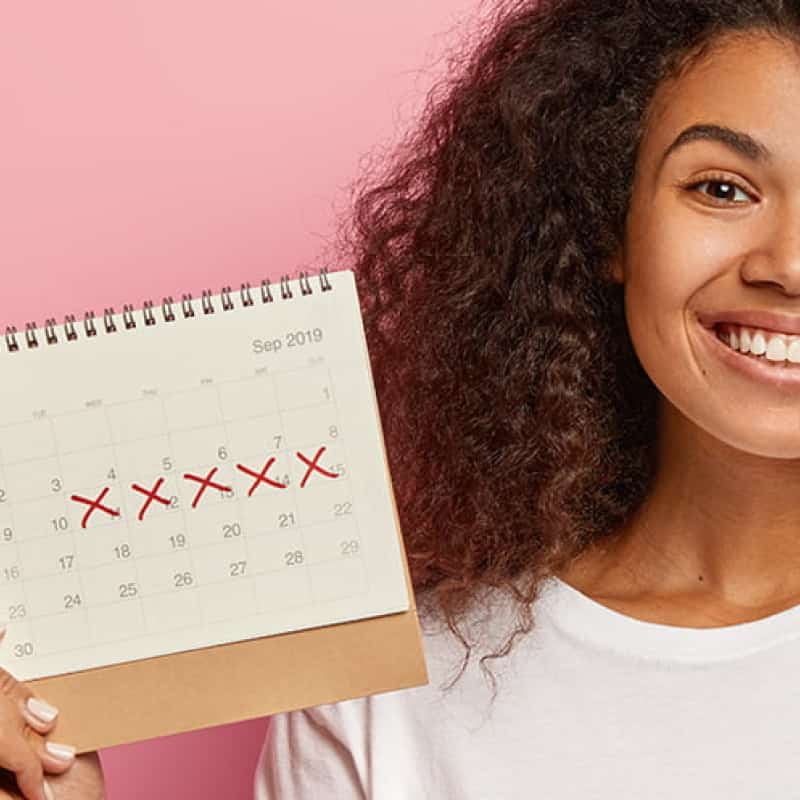 Young woman holding up simple calendar, 3 ways to delay your period image header, e-Surgery