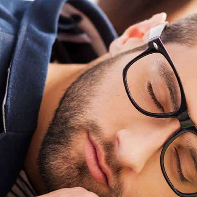 Man sleeping on a desk with a glass of water by his side | Does high blood pressure make you tired? | e-Surgery