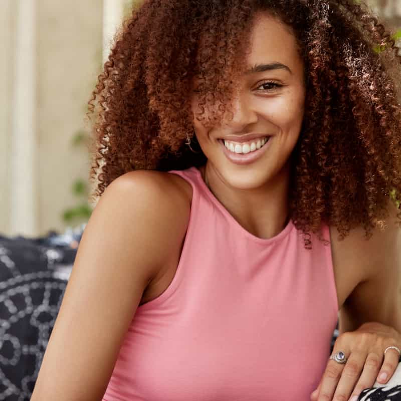young woman in a prink shirt smiling. 5 ways coming off the pill can effect your body | e-Surgery