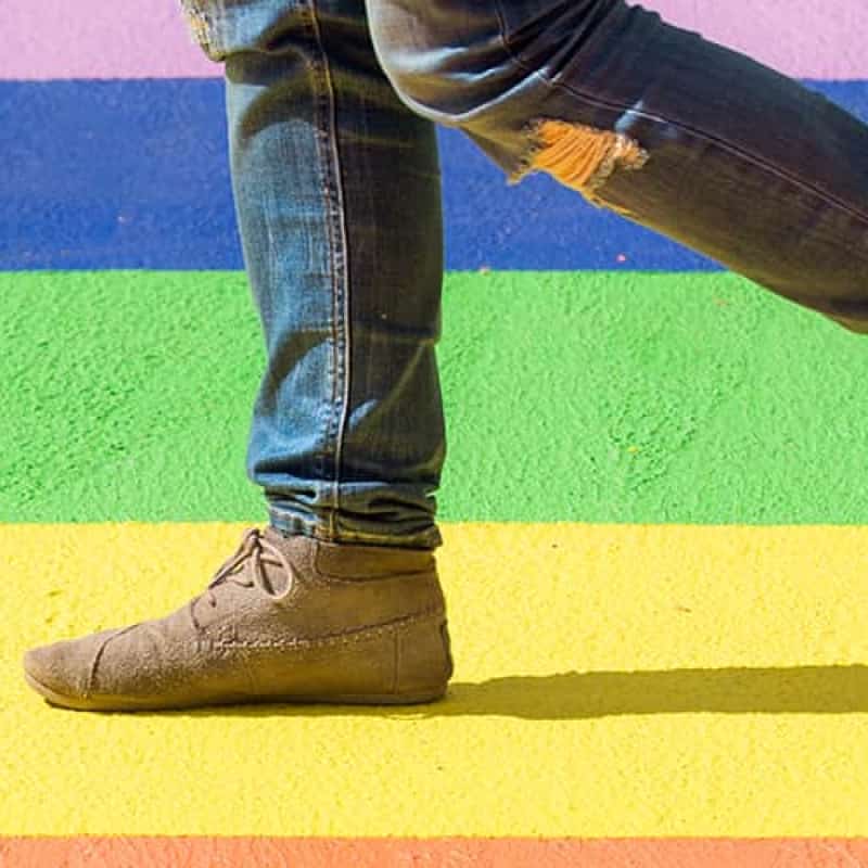 Person walking on road in rainbow colours, LGBTQ access to healthcare