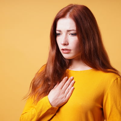 Woman holding chest with symptoms of acid reflux | e-surgery